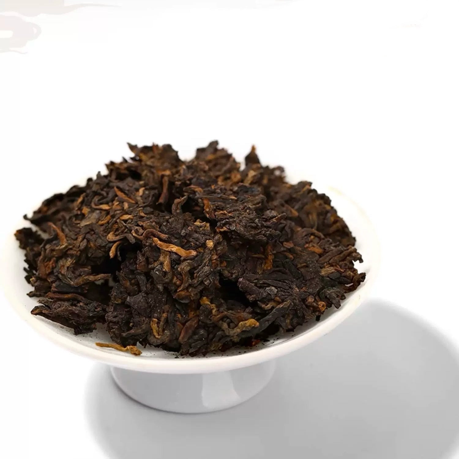 Dark brown tea leaves in a white bowl on a white background