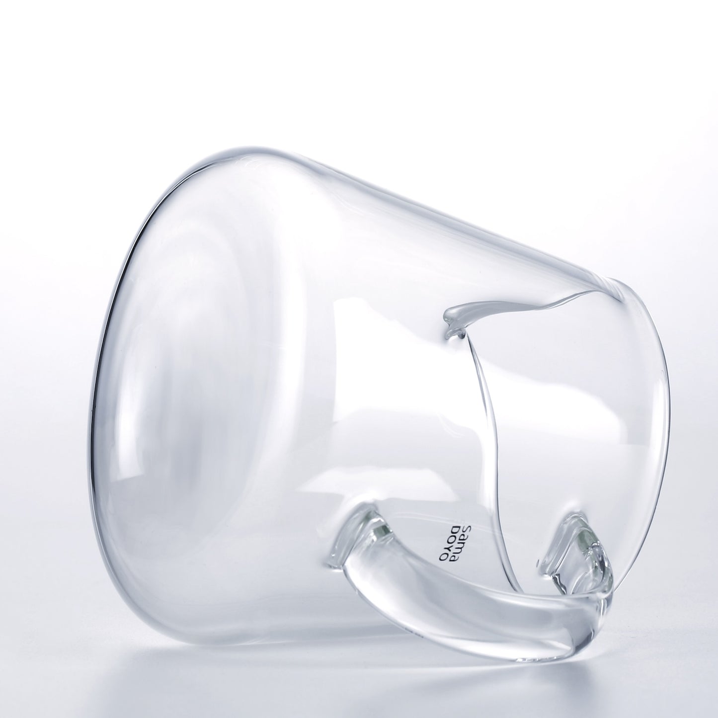 Clear glass pitcher with handle on a light gray background