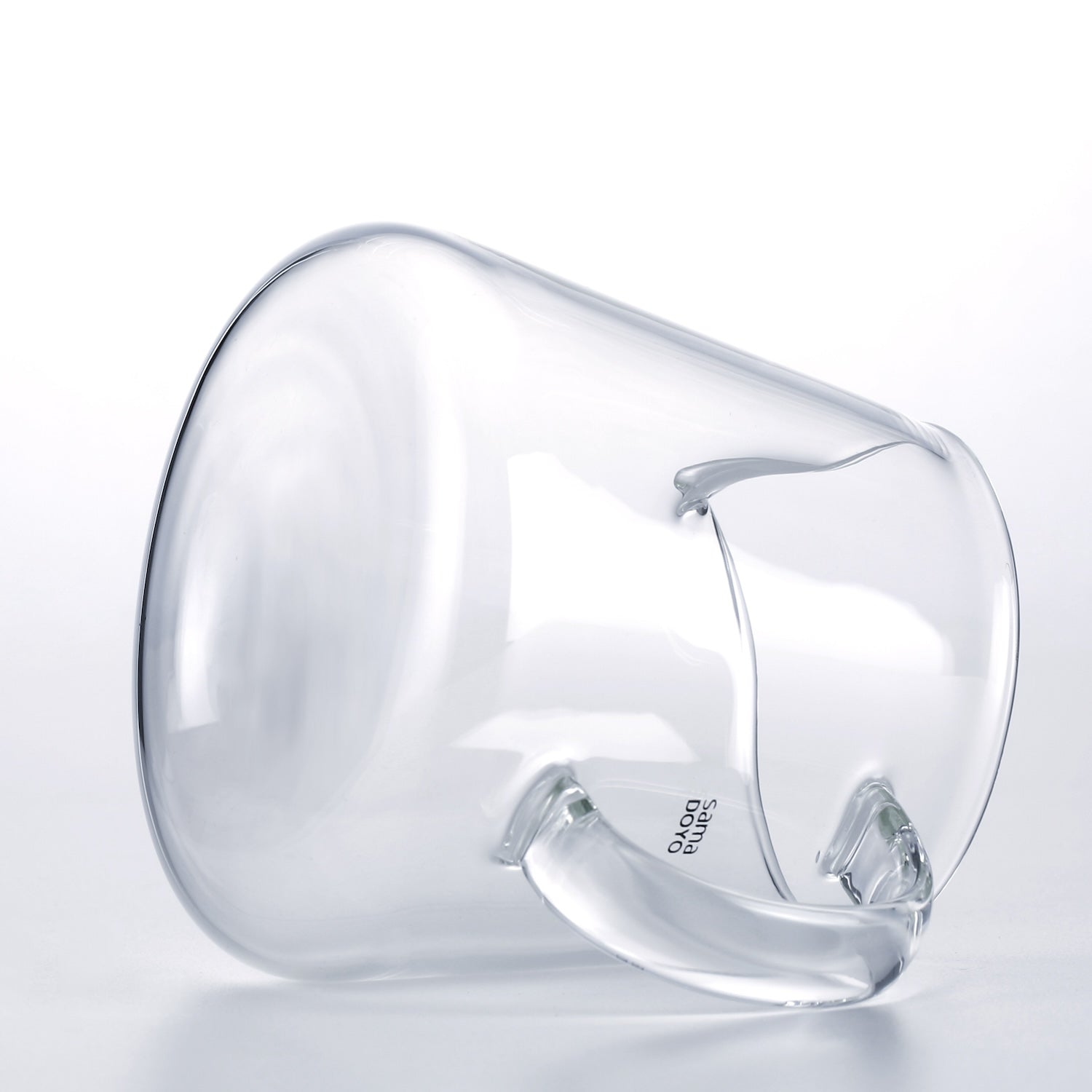 Clear glass pitcher with handle on a light gray background