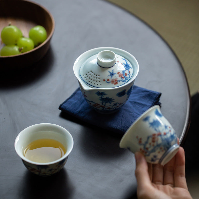 Tea set with a teapot and cups on a table, accompanied by grapes.