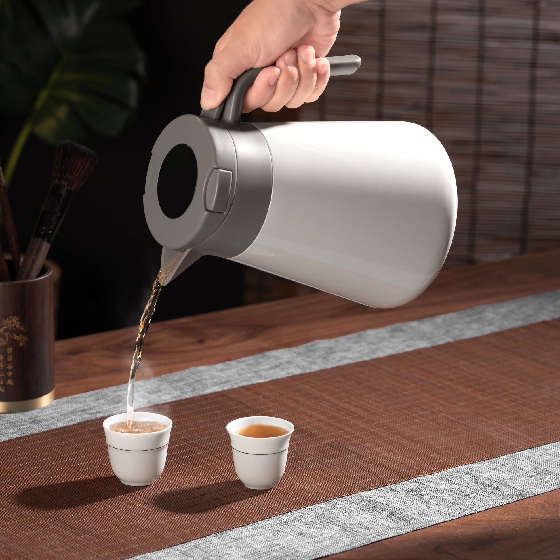 pouring tea in a cup with a thermos jug