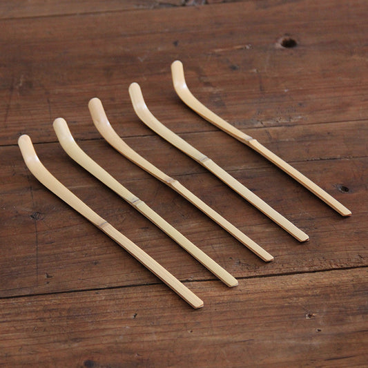 five matcha bamboo scoops on a wooden table 